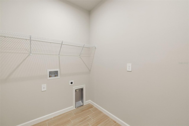 clothes washing area with hookup for an electric dryer, hookup for a washing machine, baseboards, and light wood-style floors
