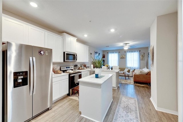 kitchen featuring kitchen peninsula, white cabinets, ceiling fan, light hardwood / wood-style floors, and stainless steel appliances