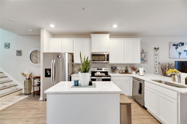 kitchen featuring sink, appliances with stainless steel finishes, kitchen peninsula, and light hardwood / wood-style floors