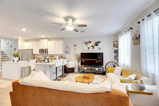 living room with light hardwood / wood-style floors, a healthy amount of sunlight, and ceiling fan