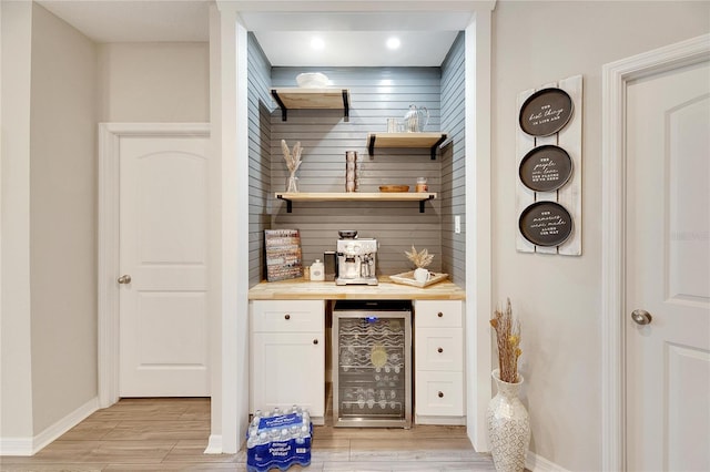 bar with butcher block counters, light hardwood / wood-style flooring, white cabinets, and beverage cooler