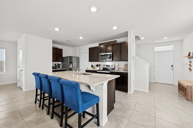 kitchen featuring a breakfast bar area, dark brown cabinetry, sink, an island with sink, and appliances with stainless steel finishes