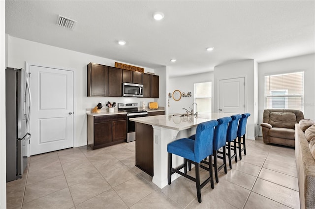 kitchen featuring an island with sink, a kitchen breakfast bar, a wealth of natural light, and stainless steel appliances