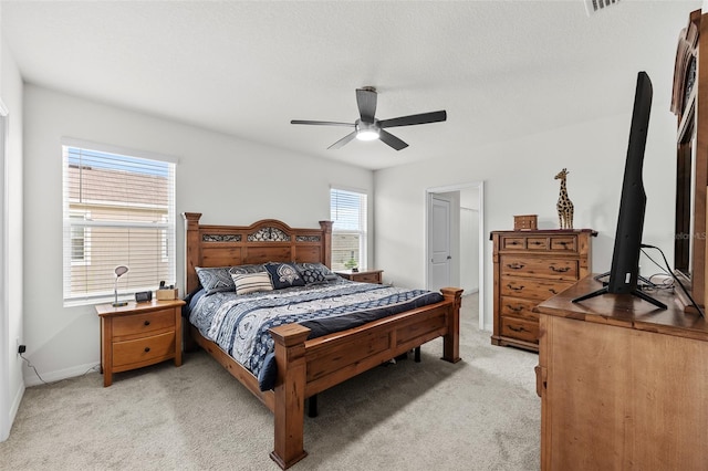 bedroom with light colored carpet, multiple windows, and ceiling fan