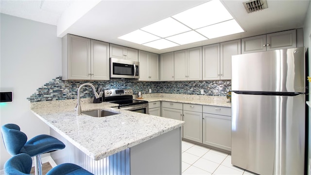 kitchen featuring sink, stainless steel appliances, kitchen peninsula, and gray cabinetry