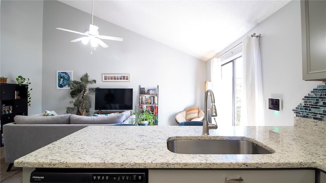 kitchen featuring lofted ceiling, light stone countertops, ceiling fan, and sink