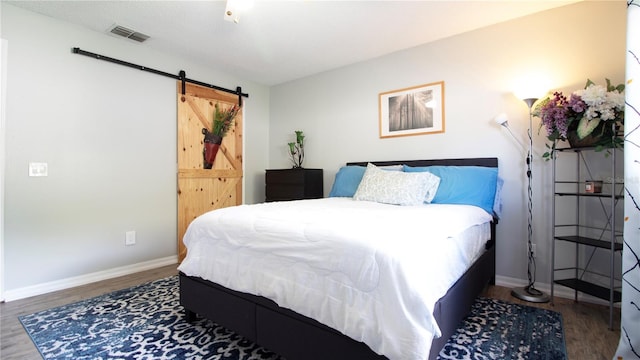 bedroom with a barn door and dark hardwood / wood-style flooring