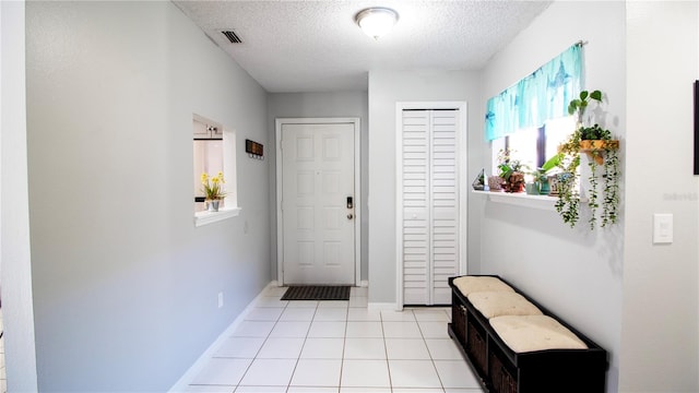 doorway to outside with light tile patterned flooring and a textured ceiling