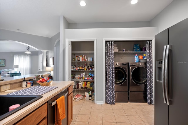 kitchen featuring washing machine and clothes dryer, sink, light tile patterned floors, appliances with stainless steel finishes, and decorative columns