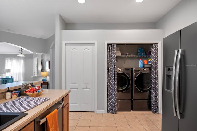 kitchen featuring sink, washer and dryer, stainless steel fridge, light tile patterned floors, and decorative columns