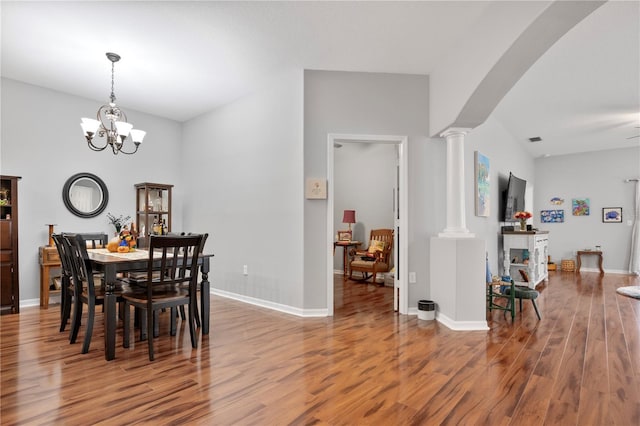 dining area featuring hardwood / wood-style flooring, a notable chandelier, and decorative columns