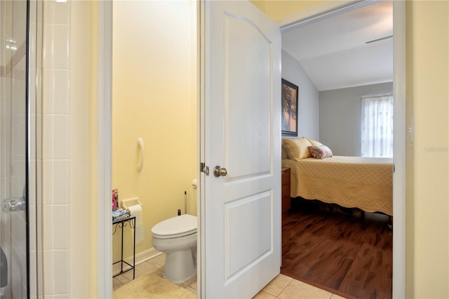 bathroom with tile patterned flooring, vaulted ceiling, and toilet