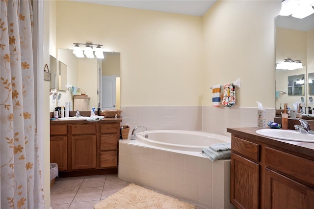 bathroom featuring tile patterned flooring, vanity, and tiled tub