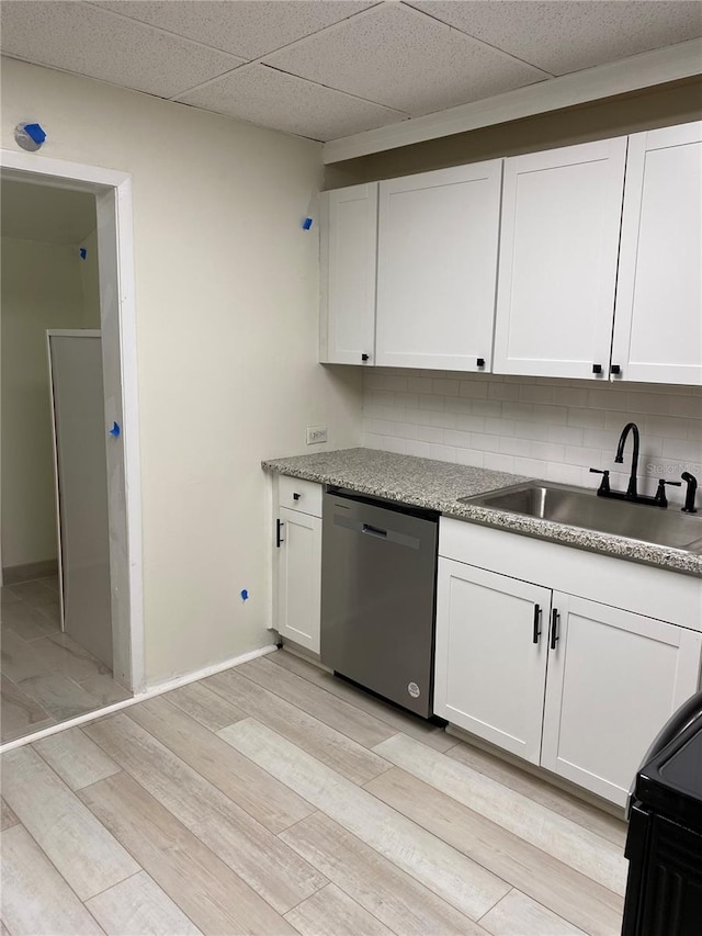 kitchen with stainless steel dishwasher, tasteful backsplash, sink, light hardwood / wood-style floors, and white cabinetry