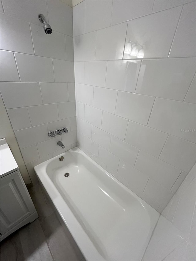 bathroom featuring tiled shower / bath and vanity