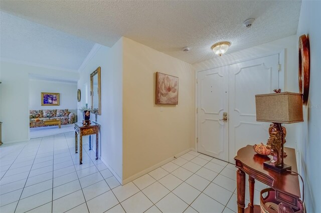 foyer entrance with crown molding, a textured ceiling, and light tile patterned flooring