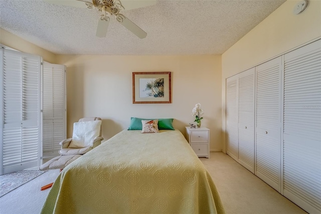 carpeted bedroom with a textured ceiling, ceiling fan, and a closet