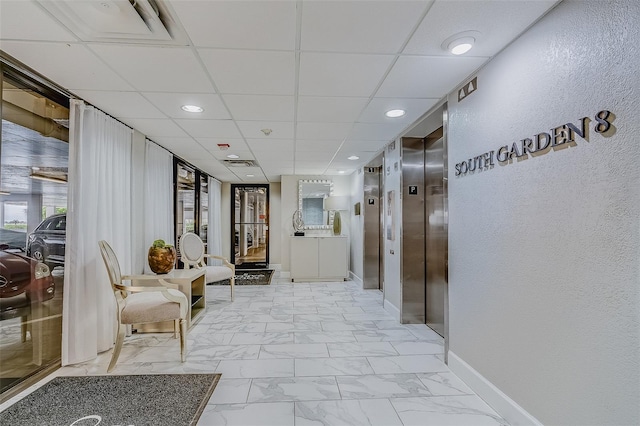 hallway featuring elevator and a drop ceiling