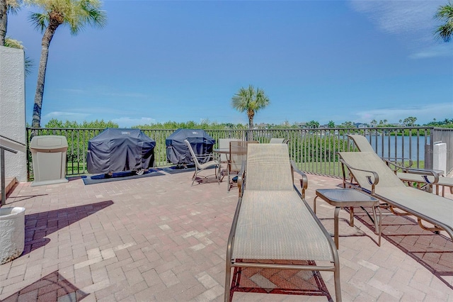 view of patio with a water view and a grill