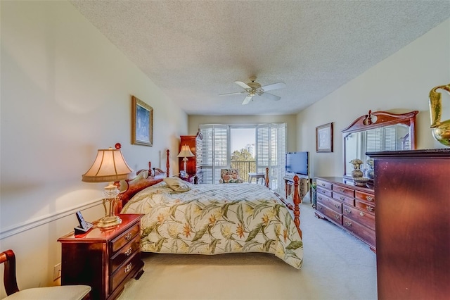 bedroom with ceiling fan, light colored carpet, and a textured ceiling