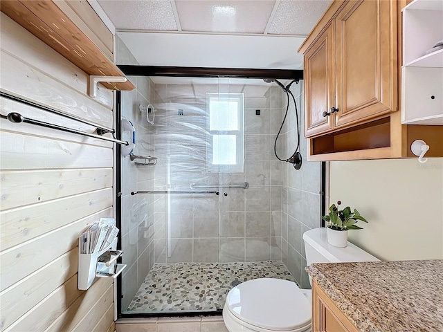 bathroom with wooden walls, a shower with door, and toilet