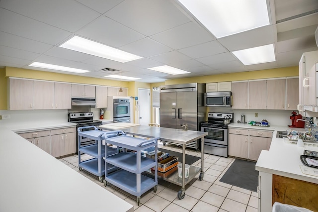 kitchen with a drop ceiling, sink, pendant lighting, and appliances with stainless steel finishes