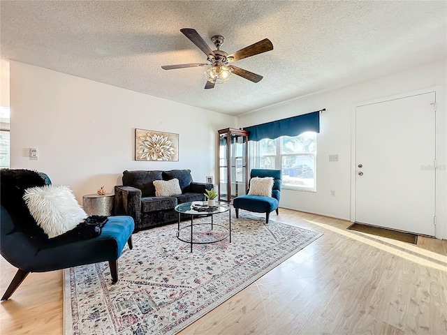 living room featuring light wood-type flooring, a textured ceiling, and ceiling fan