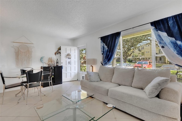 living room with a textured ceiling, light tile patterned floors, and plenty of natural light