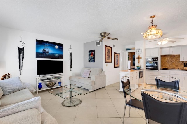 living room with a textured ceiling, light tile patterned floors, and ceiling fan with notable chandelier