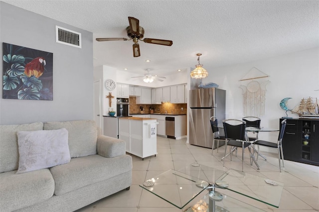 tiled living room with a textured ceiling and ceiling fan