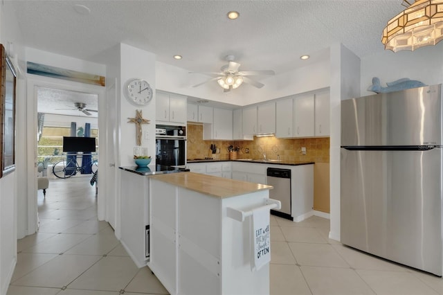 kitchen with hanging light fixtures, stainless steel appliances, white cabinetry, a textured ceiling, and tasteful backsplash