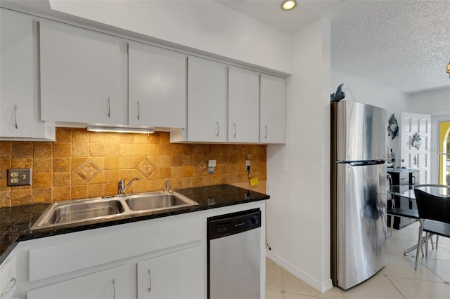 kitchen with sink, white cabinets, light tile patterned flooring, appliances with stainless steel finishes, and a textured ceiling