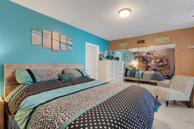 bedroom featuring a textured ceiling, a closet, and light tile patterned floors