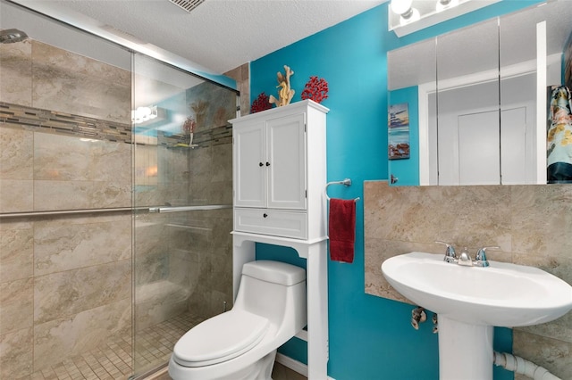 bathroom featuring toilet, tasteful backsplash, a textured ceiling, and a shower with shower door