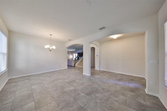 unfurnished room with ceiling fan with notable chandelier