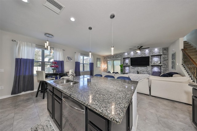 kitchen featuring hanging light fixtures, a center island with sink, ceiling fan, stainless steel dishwasher, and sink