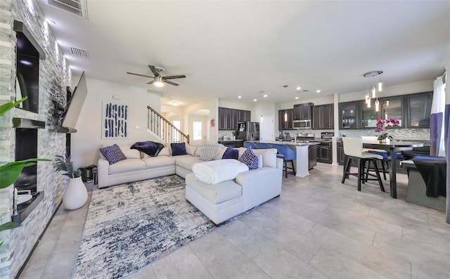 living room with ceiling fan and a stone fireplace