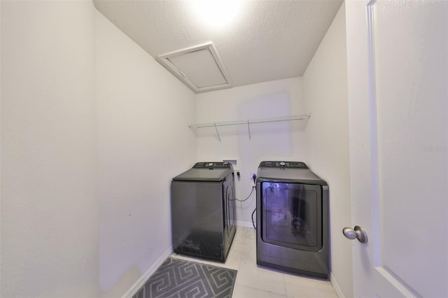 washroom featuring washer and dryer, a textured ceiling, and light tile patterned floors