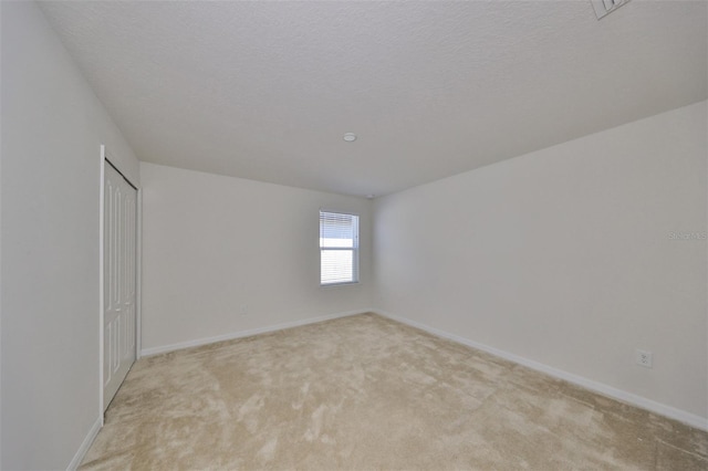 unfurnished room featuring a textured ceiling and light colored carpet