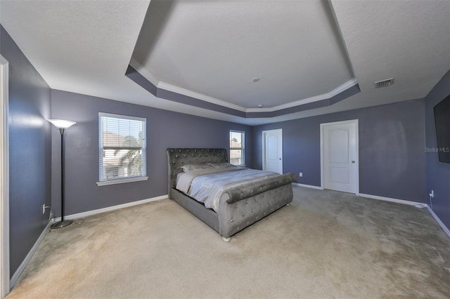 unfurnished bedroom with ornamental molding, light carpet, and a tray ceiling