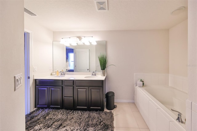 bathroom featuring vanity, a textured ceiling, tile patterned floors, and a bathtub