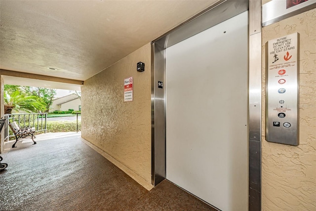 corridor with elevator, a textured ceiling, and carpet floors