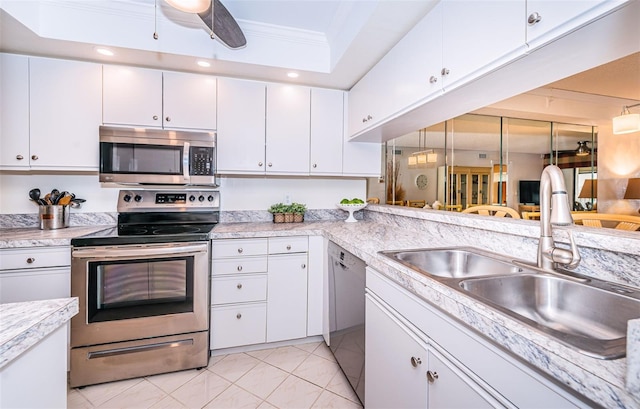 kitchen featuring sink, appliances with stainless steel finishes, ornamental molding, light tile patterned floors, and white cabinets