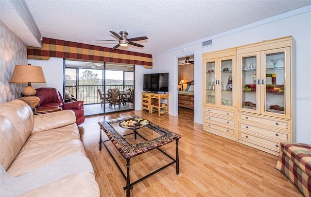 living room featuring light wood-type flooring, a textured ceiling, and ceiling fan