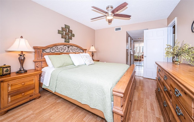 bedroom with light wood-type flooring, a textured ceiling, and ceiling fan