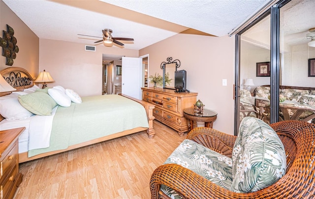 bedroom featuring light hardwood / wood-style floors, ceiling fan, and a textured ceiling