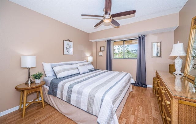 bedroom with a textured ceiling, light wood-type flooring, and ceiling fan