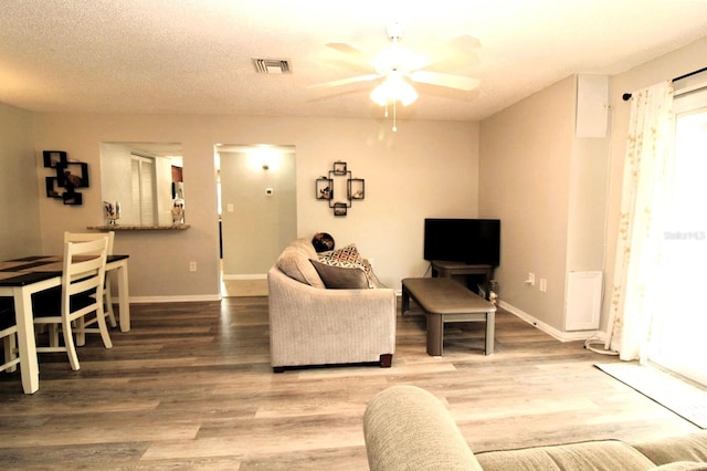 living room with hardwood / wood-style flooring, a textured ceiling, and ceiling fan