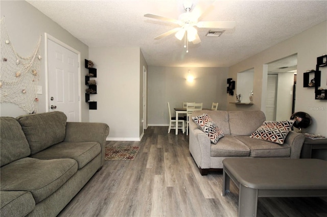 living room with hardwood / wood-style flooring, ceiling fan, and a textured ceiling