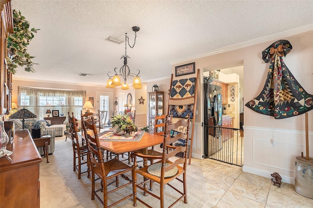 dining area with ornamental molding, a chandelier, and a textured ceiling